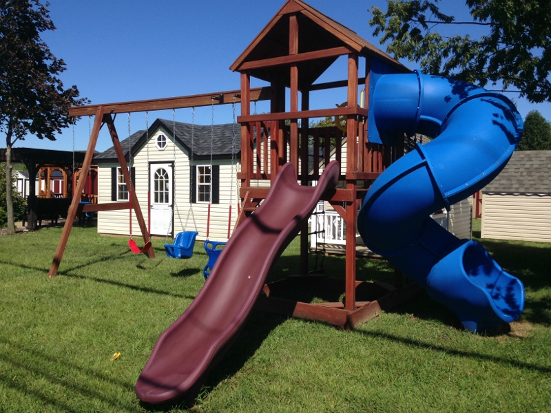 Condo 2 Shown with Tunnel Twister Slide! Rave Slide, 4-Position Swing Beam, Plastic Glider, Wood Roof, Rustic Red Stain